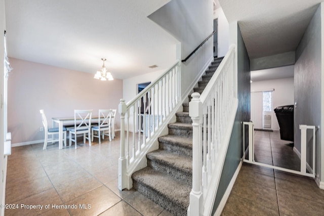 stairs featuring tile patterned floors and an inviting chandelier