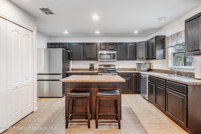 kitchen with a kitchen island, sink, light tile patterned floors, and stainless steel appliances