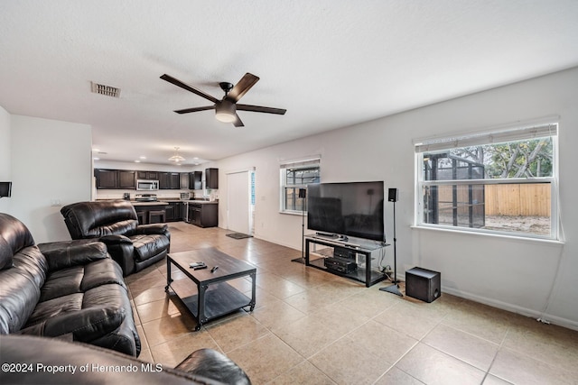 living room with ceiling fan, light tile patterned floors, and a textured ceiling