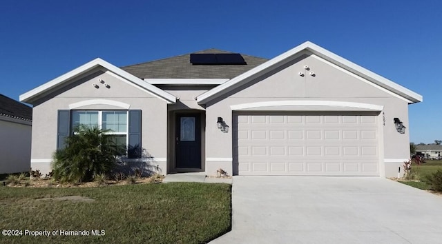 ranch-style home featuring solar panels, a garage, and a front lawn