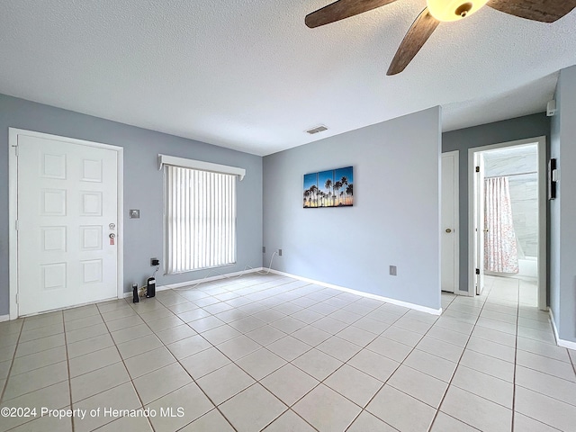 interior space featuring ceiling fan, light tile patterned floors, and a textured ceiling