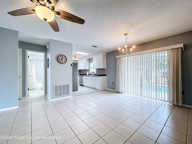 unfurnished living room with ceiling fan with notable chandelier, light tile patterned floors, a textured ceiling, and sink