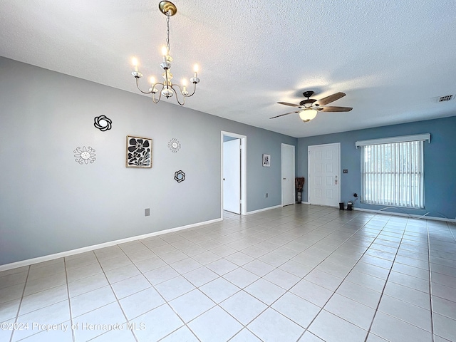 tiled spare room featuring ceiling fan with notable chandelier and a textured ceiling