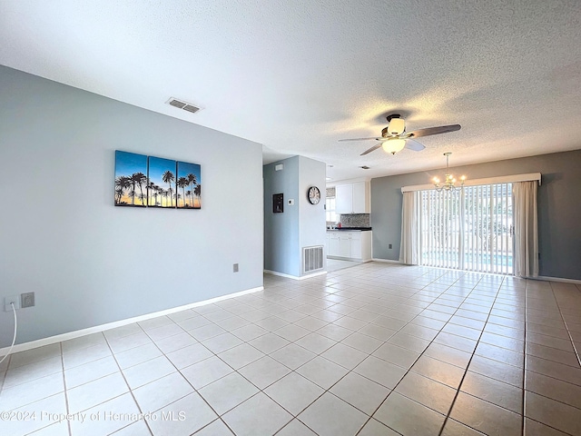 unfurnished living room with ceiling fan with notable chandelier, light tile patterned flooring, and a textured ceiling