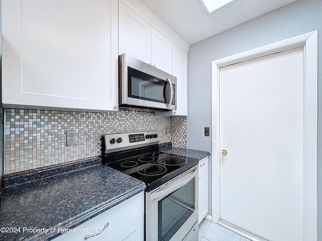 kitchen featuring white cabinets, decorative backsplash, light tile patterned flooring, and appliances with stainless steel finishes