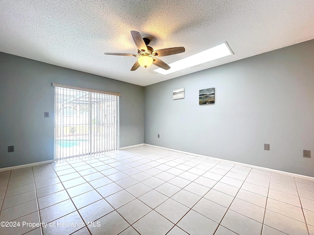 spare room featuring ceiling fan, light tile patterned floors, and a textured ceiling