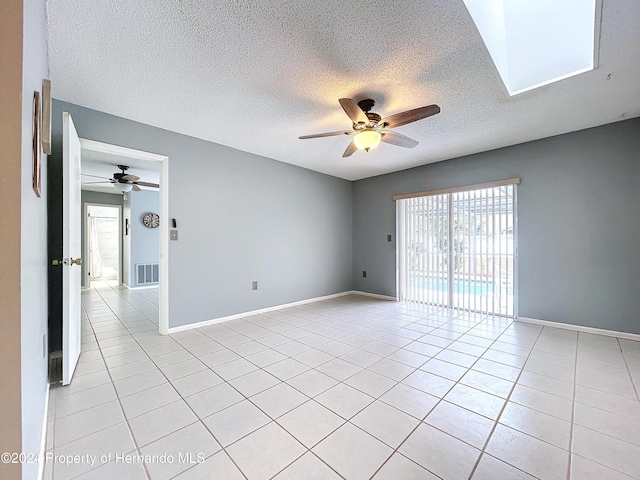 unfurnished room with ceiling fan, light tile patterned floors, and a textured ceiling