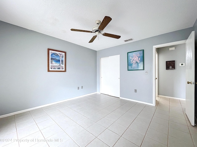 spare room featuring light tile patterned floors, a textured ceiling, and ceiling fan