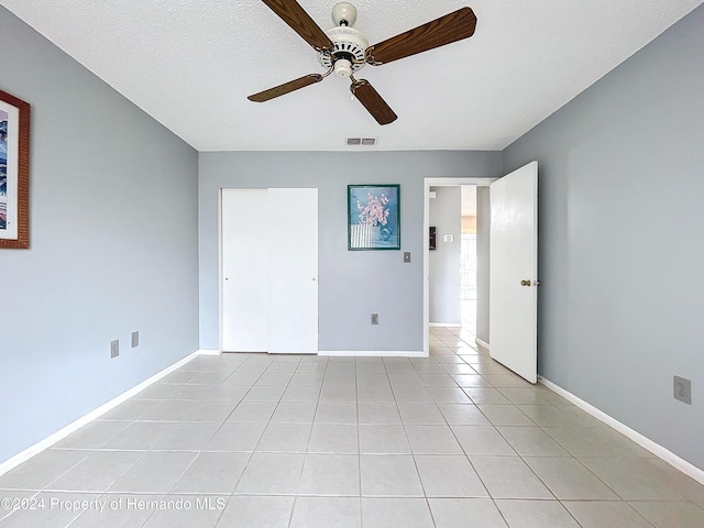 tiled empty room with a textured ceiling and ceiling fan