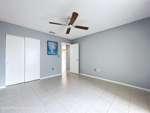 unfurnished bedroom featuring light tile patterned floors, a textured ceiling, a closet, and ceiling fan