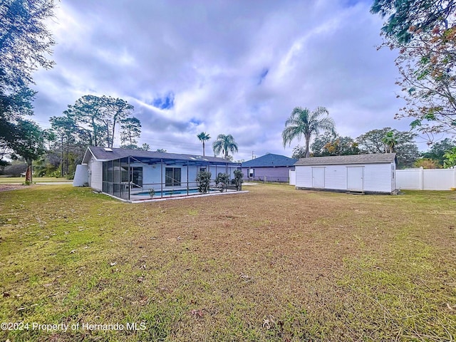 view of yard with a fenced in pool, a lanai, and an outdoor structure