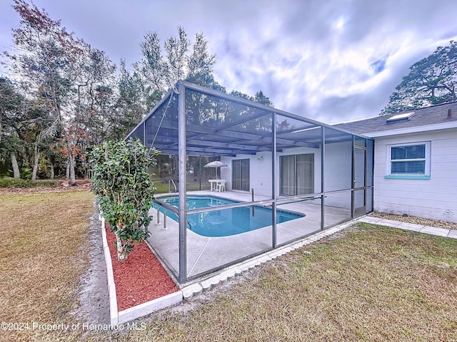 view of pool with a yard, glass enclosure, and a patio area