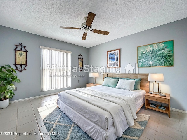 bedroom with ceiling fan, light tile patterned floors, and a textured ceiling