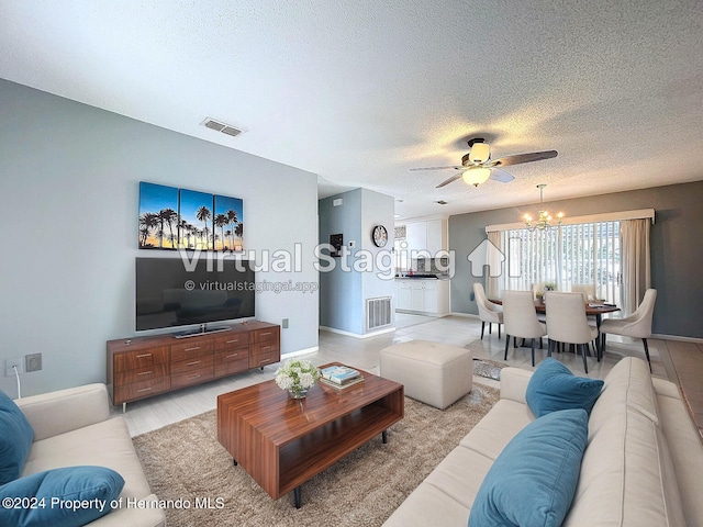 living room featuring a textured ceiling and ceiling fan with notable chandelier