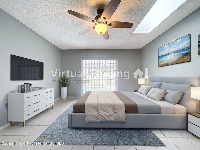 tiled bedroom featuring ceiling fan, a textured ceiling, and a skylight