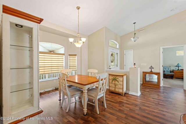 dining room with lofted ceiling, dark hardwood / wood-style flooring, and a notable chandelier