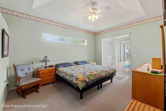 carpeted bedroom with a raised ceiling, access to exterior, and ceiling fan