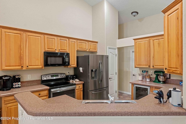 kitchen featuring kitchen peninsula, appliances with stainless steel finishes, beverage cooler, sink, and light brown cabinets