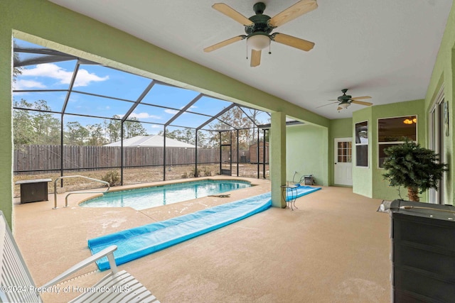 view of swimming pool featuring glass enclosure, ceiling fan, and a patio area