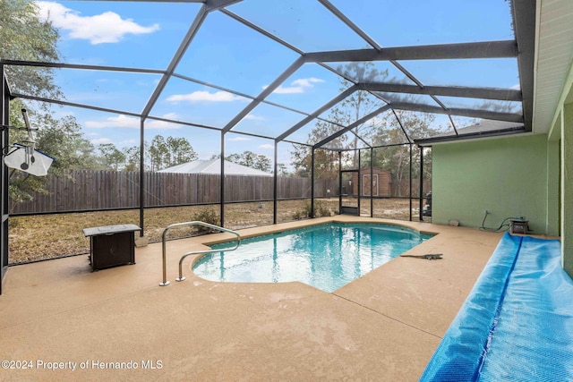 view of pool featuring a lanai, a patio, and a storage shed