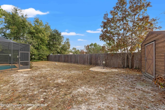 view of yard featuring a storage unit, a lanai, and a fenced in pool