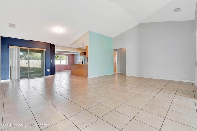 unfurnished room with sink, light tile patterned floors, and vaulted ceiling