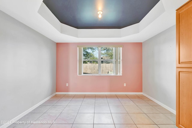 tiled spare room featuring a tray ceiling