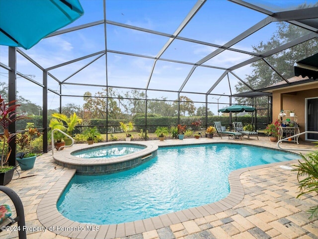 view of pool featuring an in ground hot tub, a patio, and glass enclosure