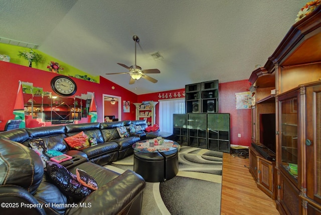 living room with hardwood / wood-style floors, a textured ceiling, vaulted ceiling, and ceiling fan