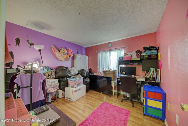 home office with light wood-type flooring and a textured ceiling