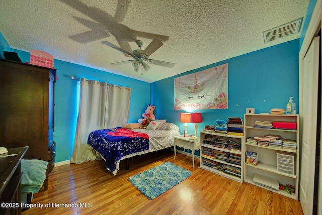 bedroom with ceiling fan, a closet, wood-type flooring, and a textured ceiling