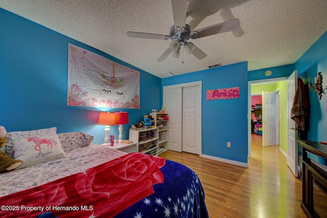 bedroom with ceiling fan, wood-type flooring, a textured ceiling, and a closet