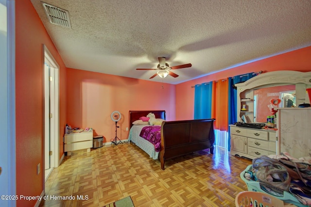 bedroom featuring ceiling fan, a textured ceiling, and light parquet flooring