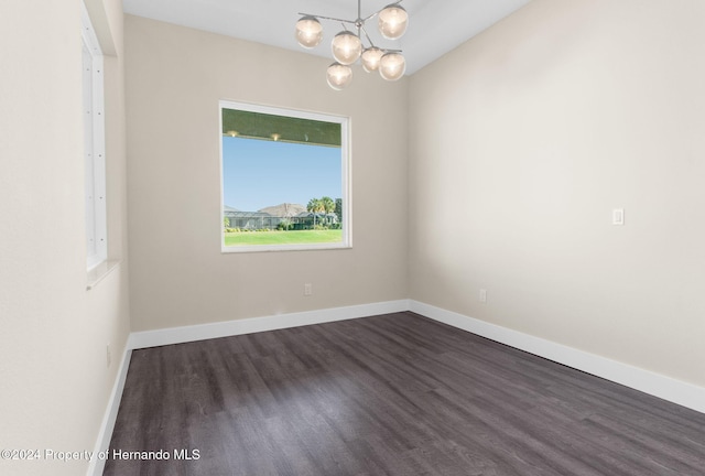 empty room featuring dark hardwood / wood-style flooring and a notable chandelier