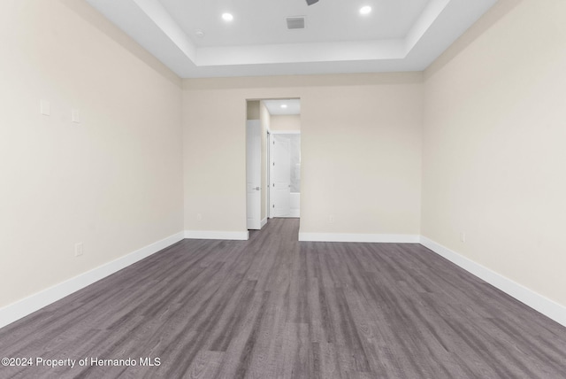 unfurnished room with a tray ceiling and dark hardwood / wood-style floors