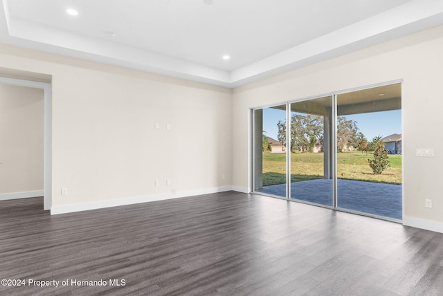 spare room featuring dark wood-type flooring and a tray ceiling