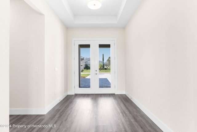 doorway to outside featuring french doors, dark hardwood / wood-style floors, and a raised ceiling