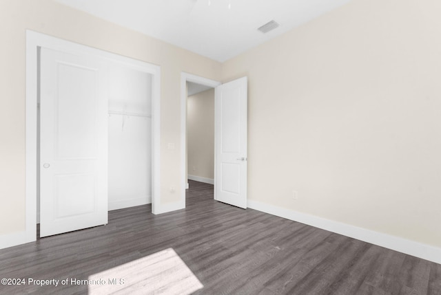 unfurnished bedroom featuring dark hardwood / wood-style flooring and a closet