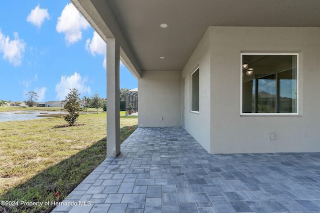 view of patio featuring glass enclosure and a water view