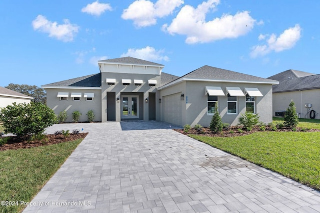 view of front of property with a front lawn, a garage, and french doors