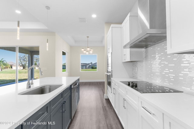 kitchen with white cabinetry, sink, pendant lighting, and wall chimney range hood