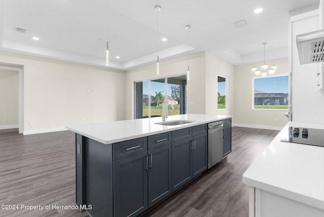 kitchen featuring pendant lighting, a center island with sink, sink, stainless steel dishwasher, and a tray ceiling