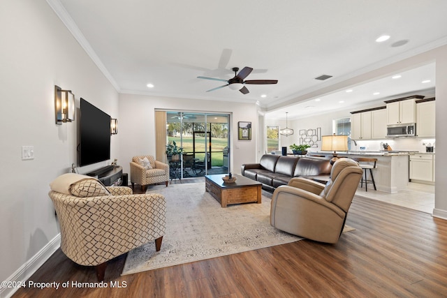 living room featuring hardwood / wood-style floors, ceiling fan, and crown molding