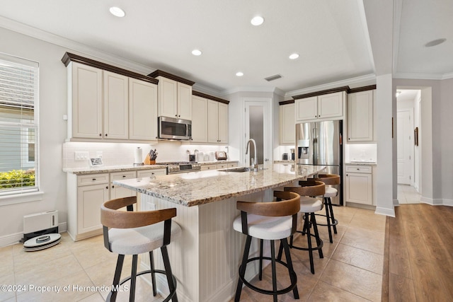 kitchen with a kitchen breakfast bar, sink, stainless steel appliances, and a center island with sink