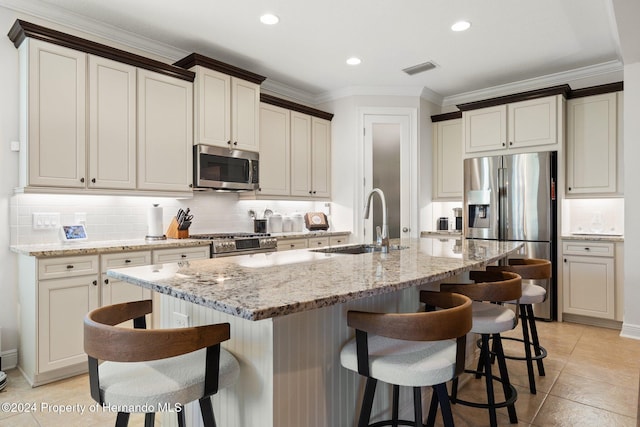 kitchen with a breakfast bar, sink, stainless steel appliances, and an island with sink