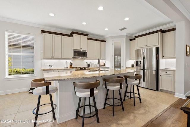 kitchen with a breakfast bar area, sink, a center island with sink, and appliances with stainless steel finishes