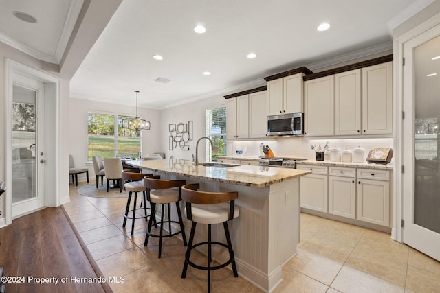 kitchen with sink, light stone countertops, an island with sink, tasteful backsplash, and decorative light fixtures