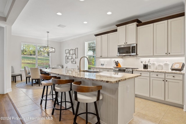 kitchen featuring stove, a center island with sink, crown molding, hanging light fixtures, and a notable chandelier