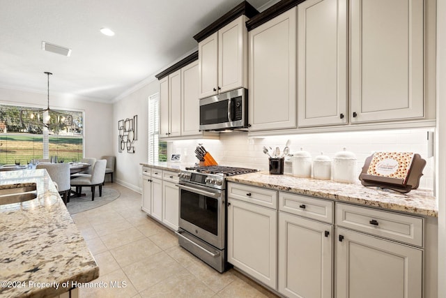 kitchen with decorative backsplash, appliances with stainless steel finishes, ornamental molding, light tile patterned floors, and decorative light fixtures