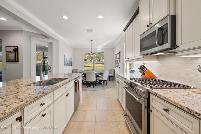 kitchen with pendant lighting, sink, light stone countertops, and stainless steel appliances